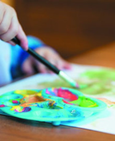 Photographie d'un atelier, plan rapproché d'un pinceau et d'une palette de peinture